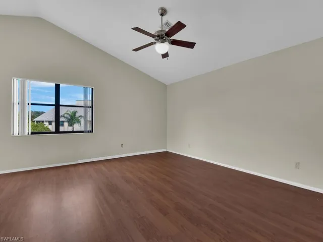 Unfurnished room with ceiling fan, dark hardwood / wood-style floors, and vaulted ceiling