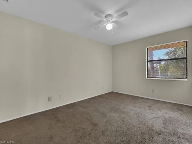 Empty room featuring dark carpet and ceiling fan
