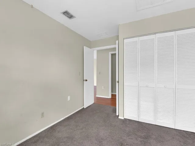 Unfurnished bedroom featuring dark carpet and a closet