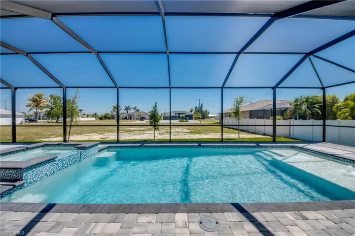 View of swimming pool featuring a lawn, a pool with connected hot tub, a lanai, and a patio area
