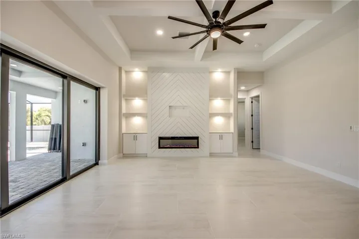Unfurnished living room featuring a ceiling fan, baseboards, a fireplace, and recessed lighting