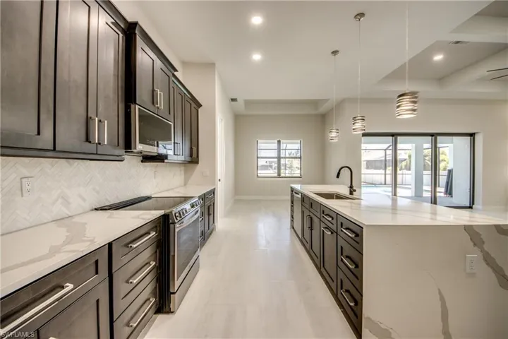 Kitchen featuring a sink, tasteful backsplash, light stone countertops, stainless steel appliances, and recessed lighting