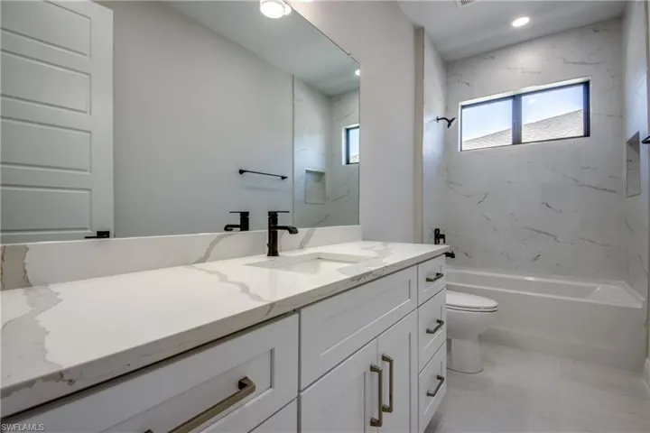 Bathroom featuring toilet, vanity, and bathtub / shower combination