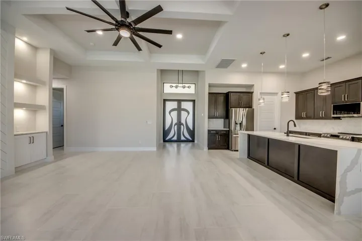 Kitchen with ceiling fan, backsplash, dark brown cabinets, and appliances with stainless steel finishes