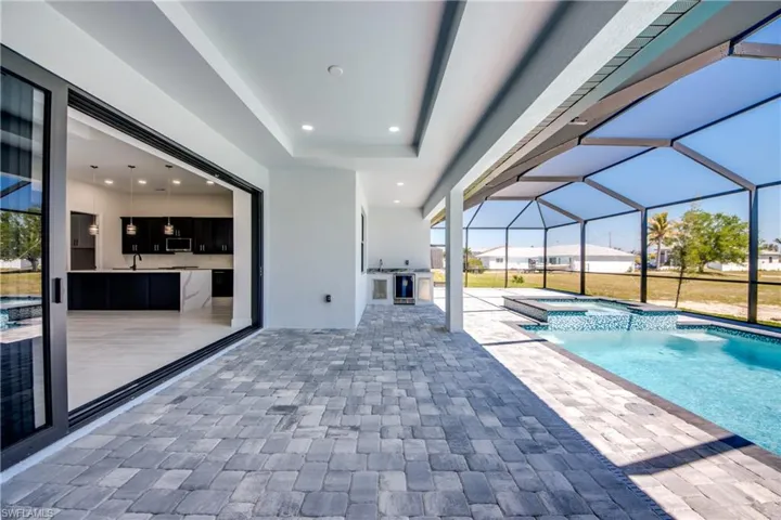 View of pool with a pool with connected hot tub, area for grilling, a lanai, and a patio