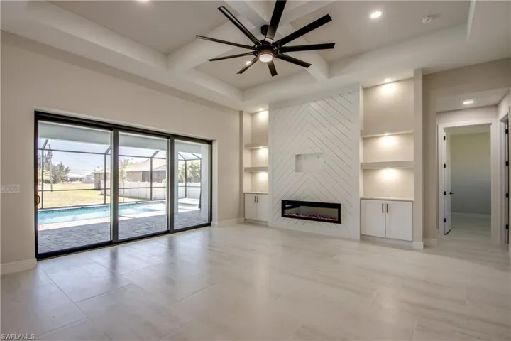 Unfurnished living room featuring baseboards, ceiling fan, a fireplace, built in features, and coffered ceiling