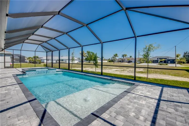 View of pool with a pool with connected hot tub, a lanai, a residential view, a lawn, and a patio area