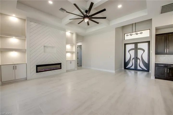 Unfurnished living room featuring visible vents, french doors, coffered ceiling, and a ceiling fan