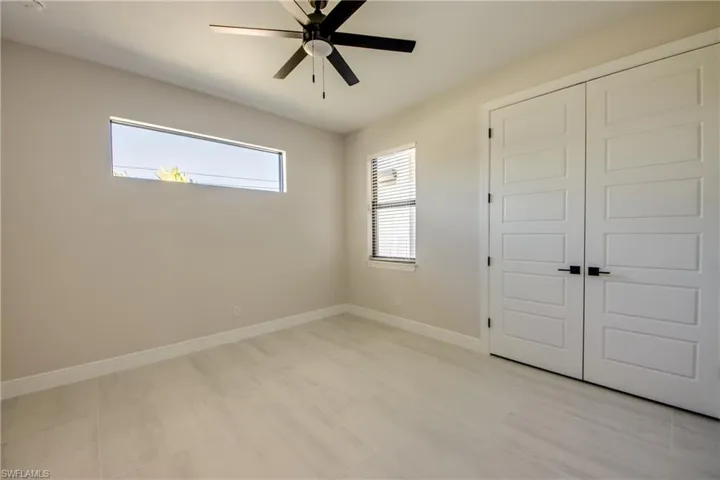 Unfurnished bedroom featuring baseboards, a closet, light tile patterned floors, and a ceiling fan