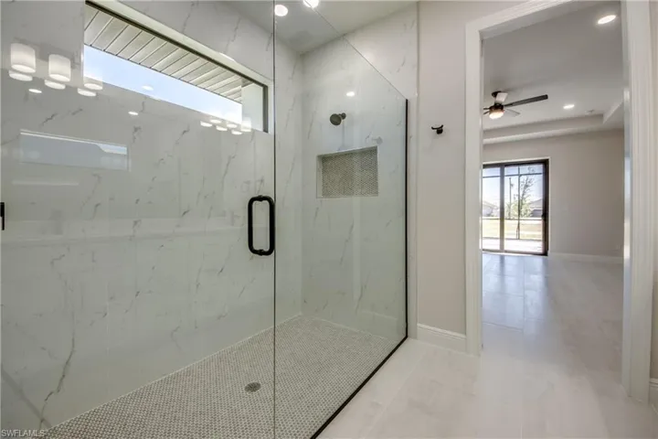 Bathroom featuring baseboards, ceiling fan, a marble finish shower, and recessed lighting