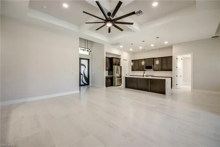 Kitchen with open floor plan, dark brown cabinets, a ceiling fan, and appliances with stainless steel finishes