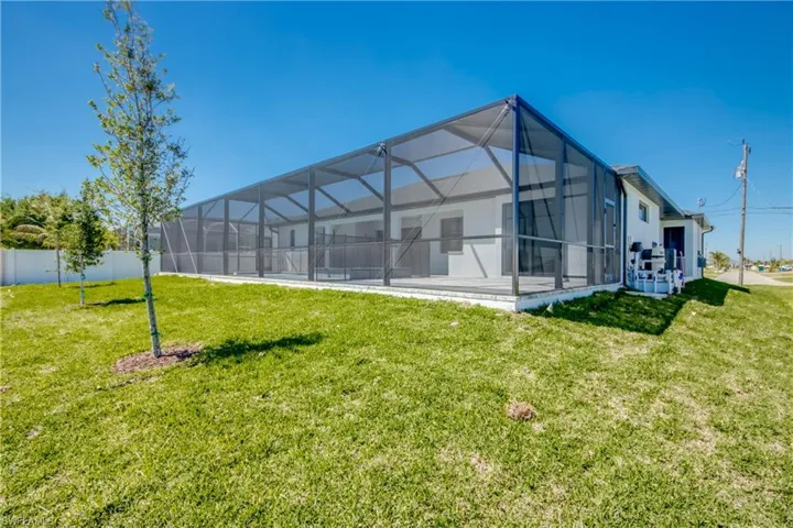 Rear view of house with a yard, fence, and a lanai