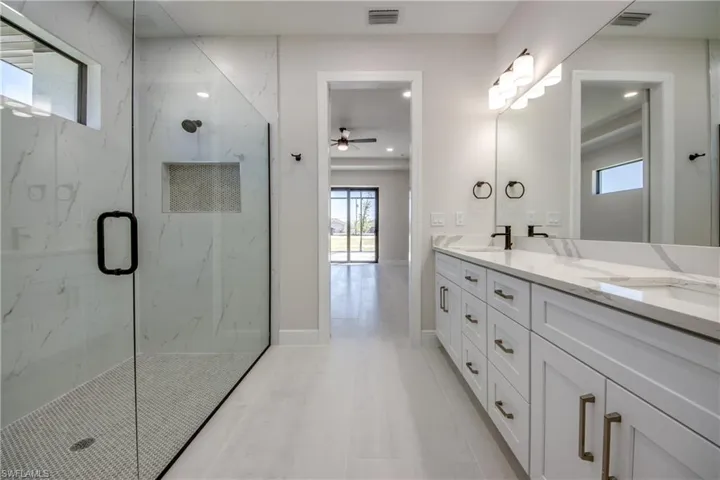 Bathroom featuring a sink, a marble finish shower, ceiling fan, and visible vents
