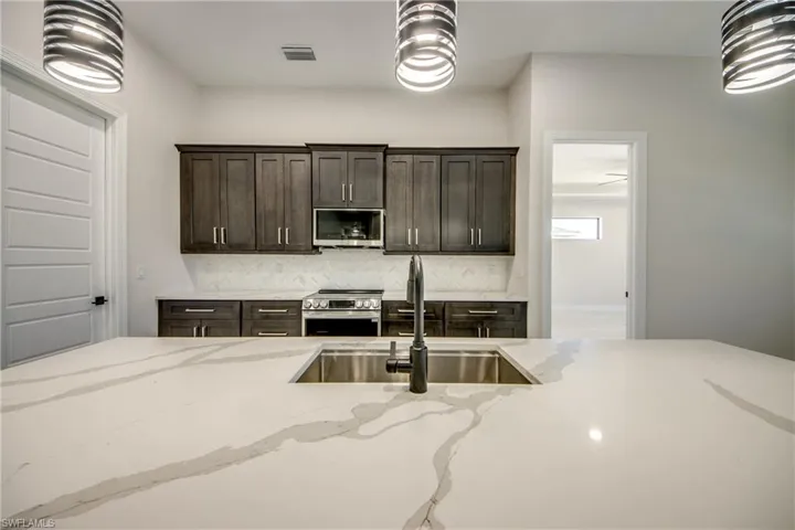 Kitchen featuring a sink, visible vents, decorative light fixtures, and appliances with stainless steel finishes