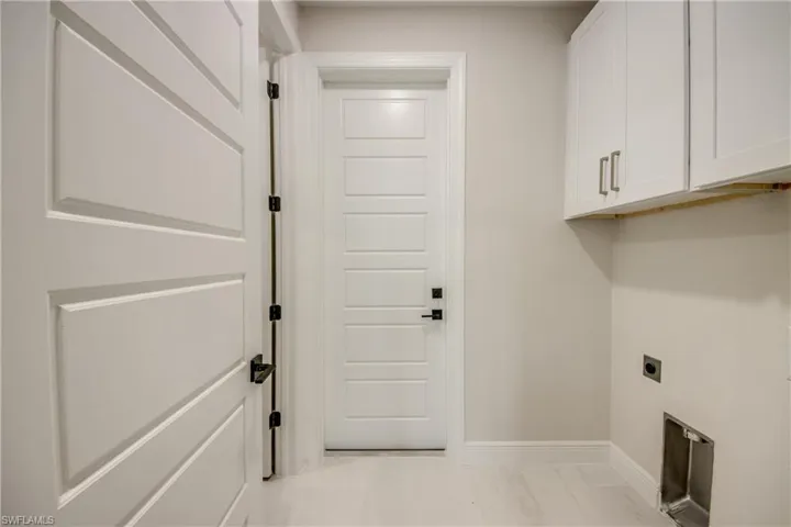 Laundry area with baseboards, cabinet space, hookup for an electric dryer, and marble finish floor
