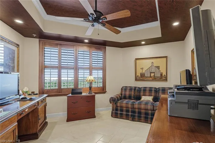 Office space with a tray ceiling, ornamental molding, recessed lighting, a ceiling fan, and light tile patterned floors