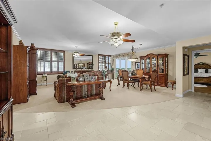 Living area featuring a ceiling fan, light colored carpet, and ornamental molding