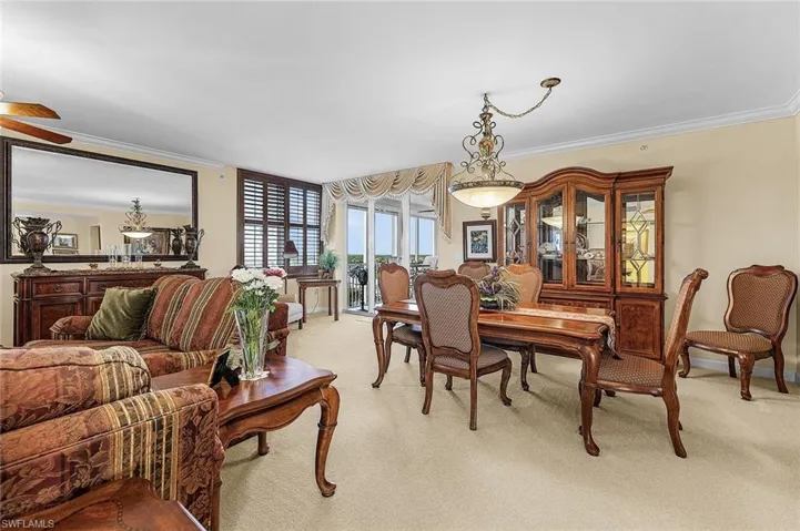 Dining area with ornamental molding, light colored carpet, and a ceiling fan