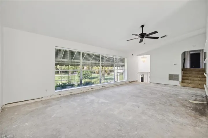 Unfurnished living room with concrete floors, vaulted ceiling, and ceiling fan