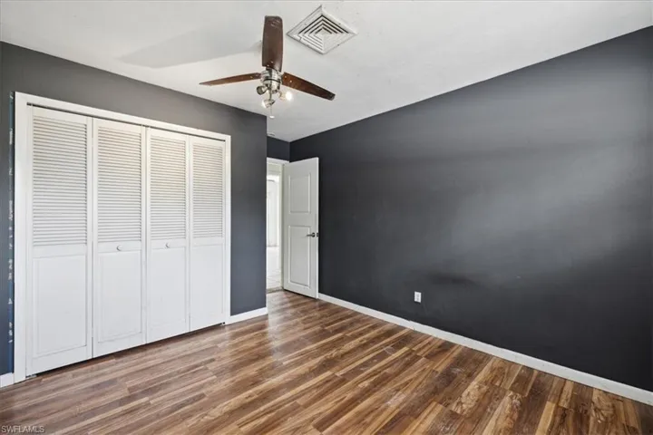 Unfurnished bedroom with a closet, ceiling fan, and dark hardwood / wood-style floors