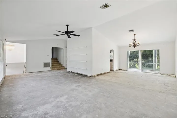 Unfurnished living room with vaulted ceiling and ceiling fan with notable chandelier