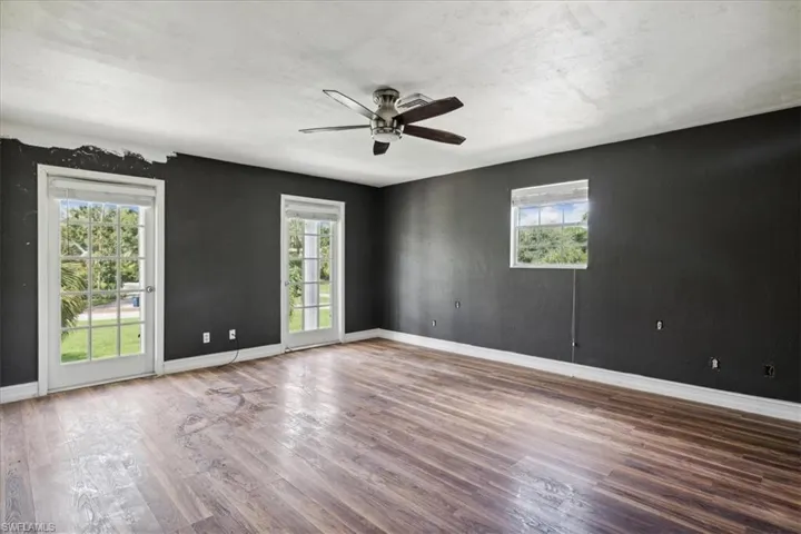 Empty room featuring plenty of natural light, wood-type flooring, and ceiling fan