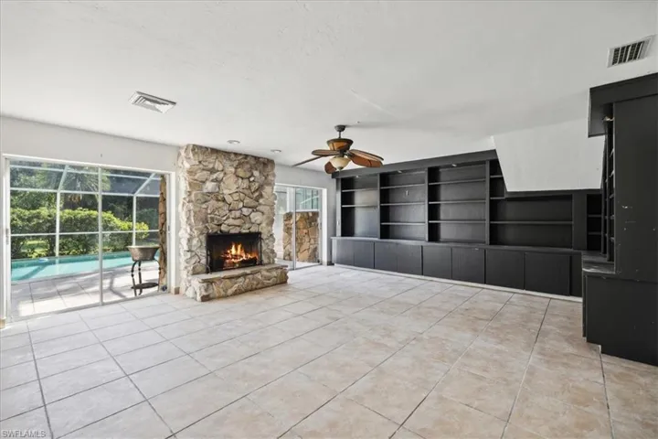 Unfurnished living room featuring a fireplace, built in shelves, a textured ceiling, light tile patterned floors, and ceiling fan