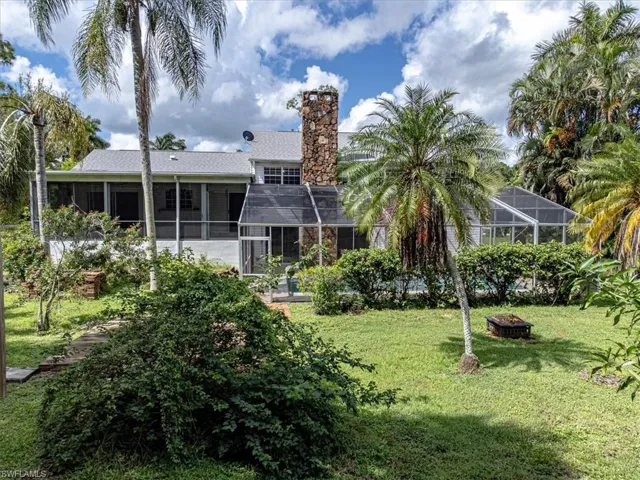 Back of house featuring glass enclosure, a yard, and a fire pit