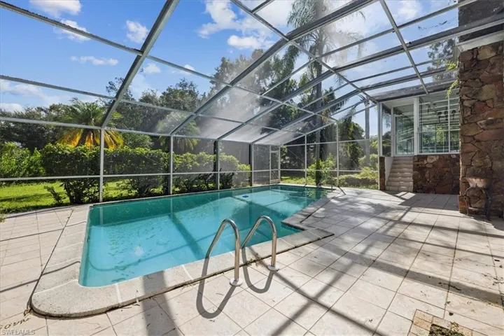 View of swimming pool with enclosure and a patio area