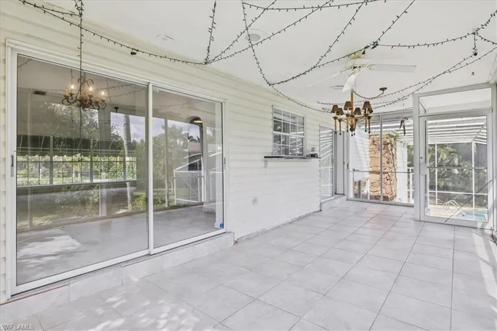 Unfurnished sunroom featuring ceiling fan with notable chandelier