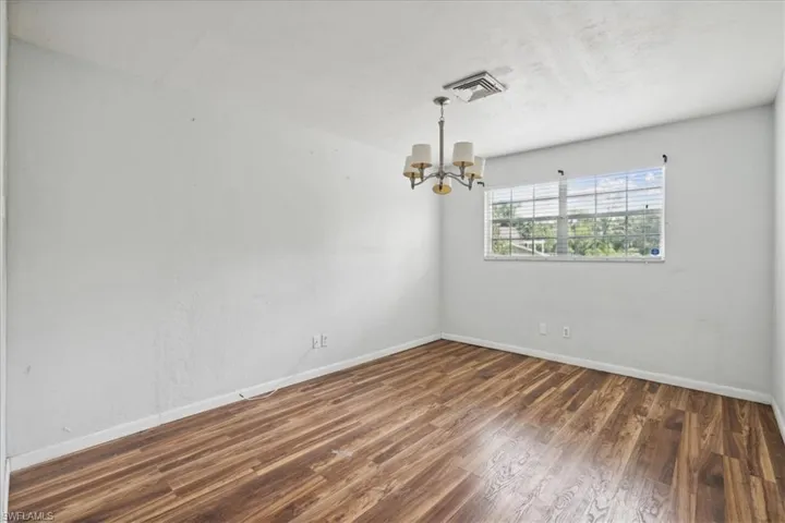 Empty room featuring dark hardwood / wood-style floors and a chandelier