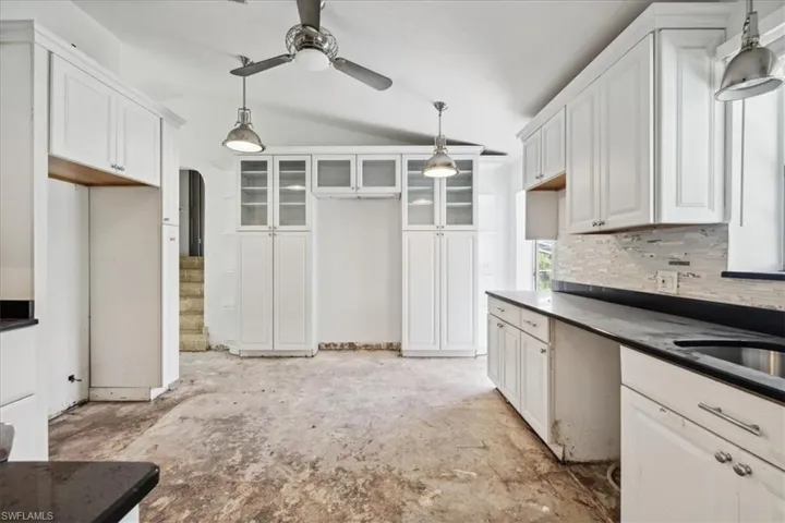 Kitchen with white cabinets, pendant lighting, vaulted ceiling, and ceiling fan