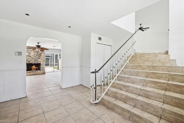 Stairway with ceiling fan, a fireplace, and tile patterned flooring