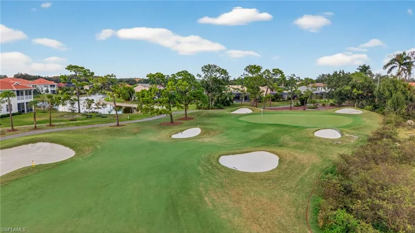 Golf course setting featuring manicured fairways, sand bunkers, putting green, water feature, and mature trees