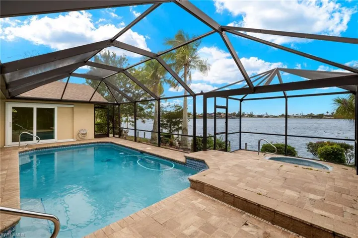 Swimming pool featuring glass enclosure, a sunroom, and a water view