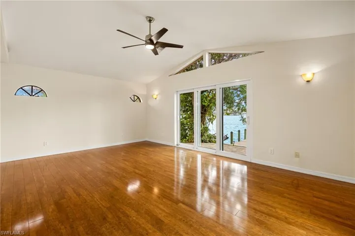 Unfurnished room with hardwood / wood-style flooring, a ceiling fan, and high vaulted ceiling