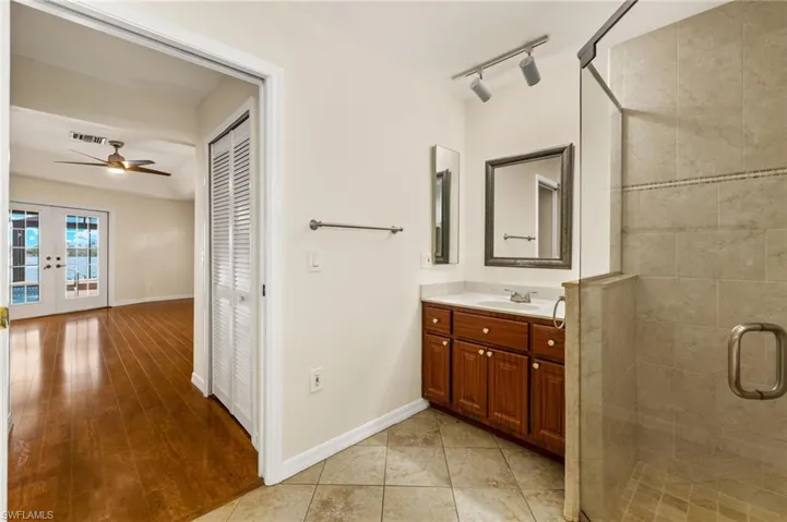 Full bathroom featuring vanity, a shower stall, french doors, a closet, and ceiling fan