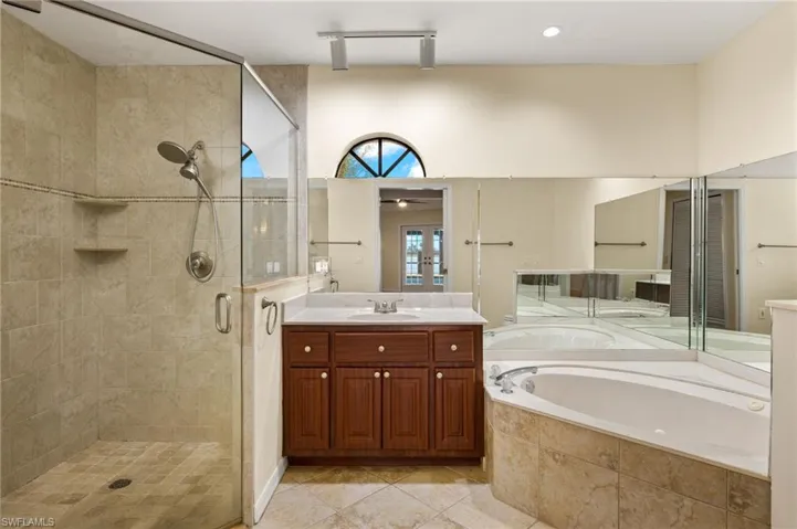 Bathroom featuring a stall shower, a garden tub, vanity, and light tile patterned floors