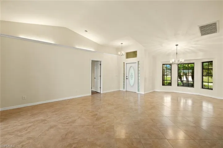 Spare room with a chandelier, lofted ceiling, and light tile patterned floors