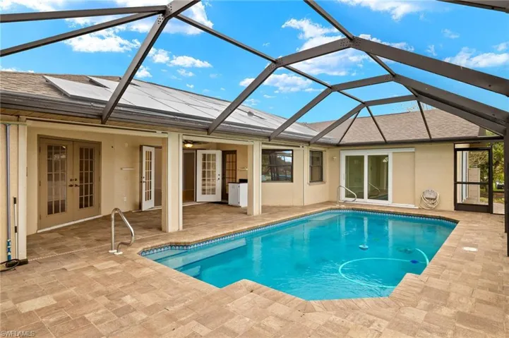 Back of house with french doors, glass enclosure, a sunroom, and a patio