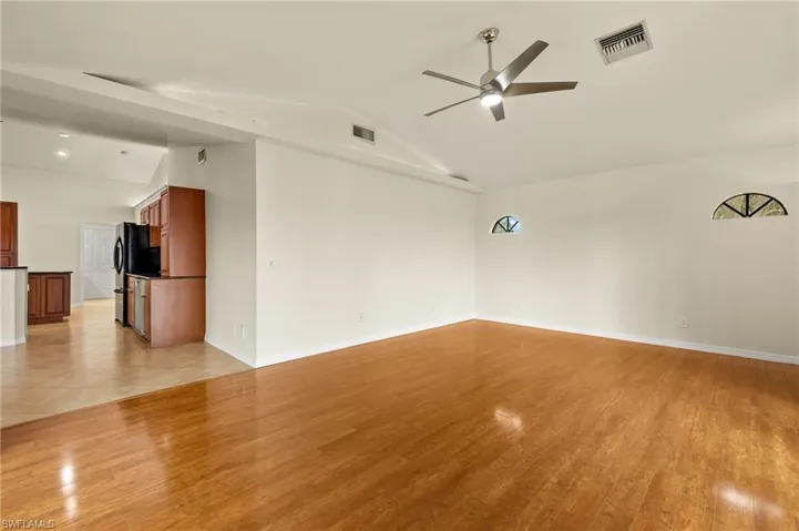 Spare room featuring light wood-style flooring, lofted ceiling, and ceiling fan