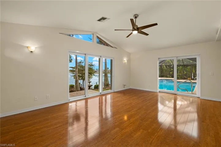 Unfurnished room featuring healthy amount of natural light, ceiling fan, light wood-type flooring, and high vaulted ceiling