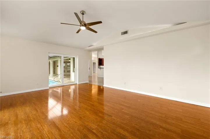 Empty room with lofted ceiling, wood finished floors, and ceiling fan