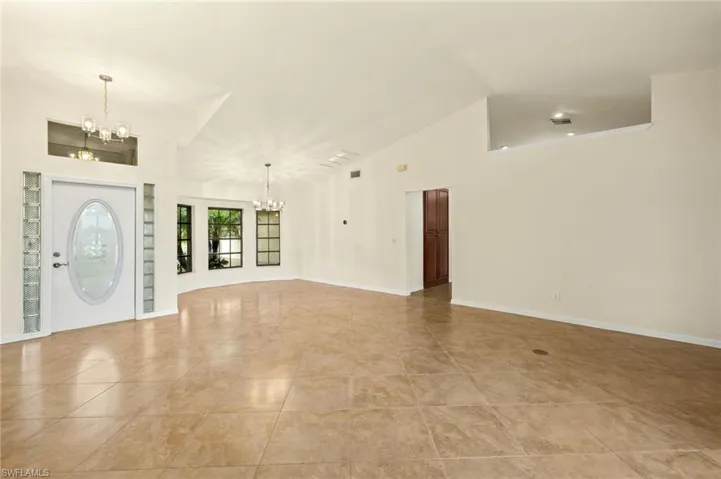 Foyer entrance featuring a chandelier, vaulted ceiling, and light tile patterned floors