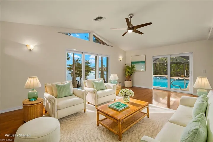 Living room featuring wood finished floors, a ceiling fan, high vaulted ceiling, and a sunroom