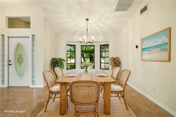 Tiled dining room with a chandelier and baseboards