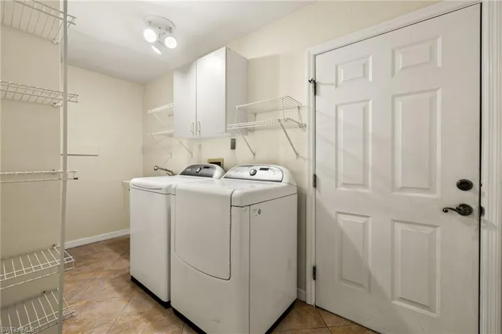 Washroom with light tile patterned flooring, separate washer and dryer, and cabinet space