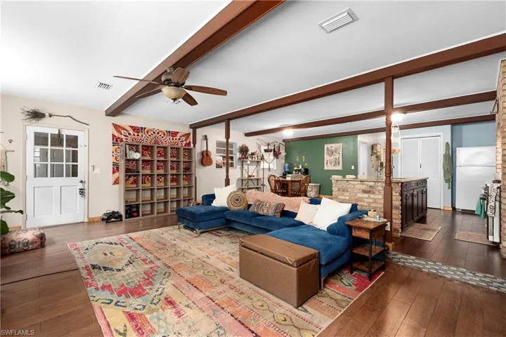 Living room featuring beamed ceiling, ceiling fan, and dark hardwood / wood-style floors