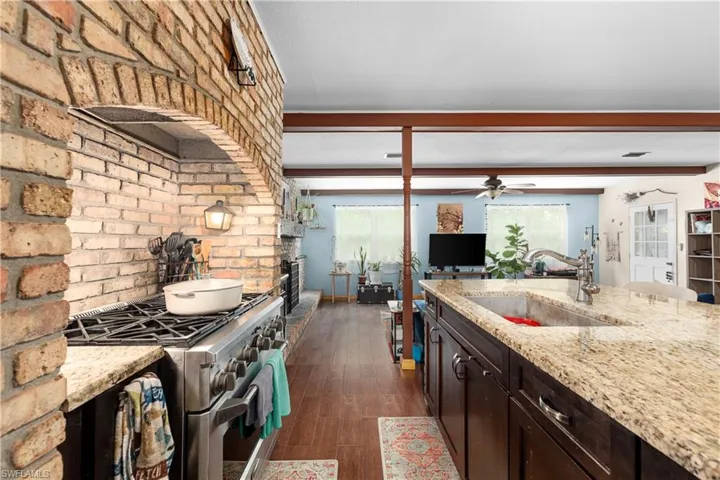 Kitchen with beamed ceiling, high end stainless steel range oven, light stone counters, and sink