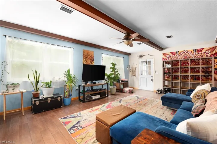 Living room with ceiling fan, hardwood / wood-style floors, and beam ceiling